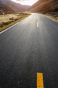 Colorful landscape with beautiful mountain road with a perfect asphalt. High rocks, blue sky at sunrise in summer.