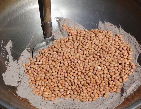 A market vendor roasts peanuts with salt and sand. They are a popular Chinese snack food.

