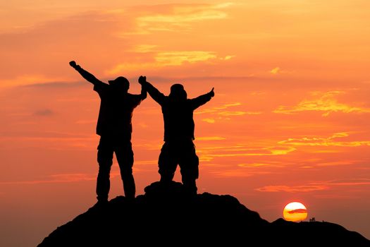 Silhouette of man hold up hands on the peak of mountain,success concept