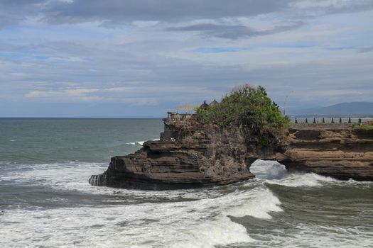 Batu Bolong beach which has an tourism attraction spot close to Tanah Lot temple. Huge hole in rock cliff below Pura Batu Bolong temple. Hindu Temple on the Beatiful Rock in the morning light, Bali.