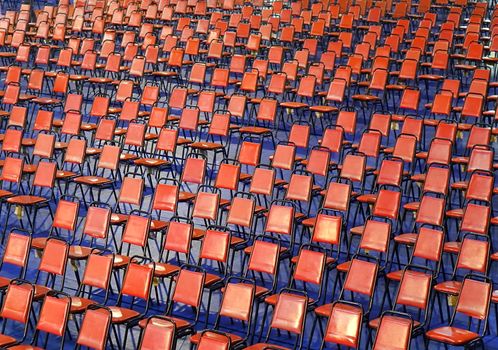 Rows of red chairs are set up for a public event

