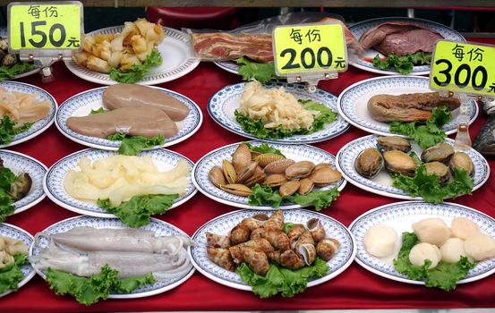 A nightmarket food stall displays a choice of raw seafood dishes