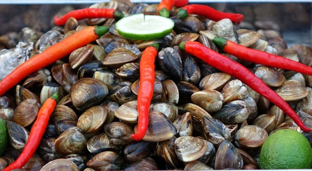 A street vendor sells fresh clams with chilies and lime slices