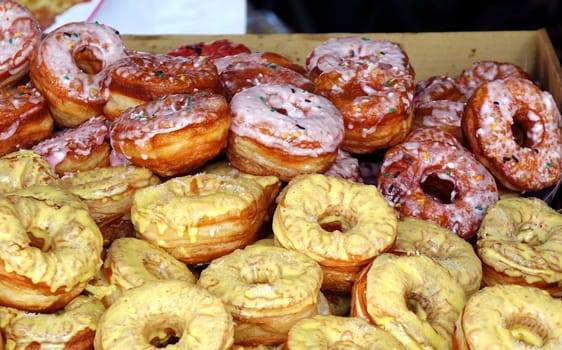 Stacks of fresh sugar frosted donuts are sold at an outdoor market
