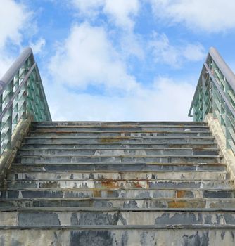 A stairway that leads up to a blue sky and white clouds
