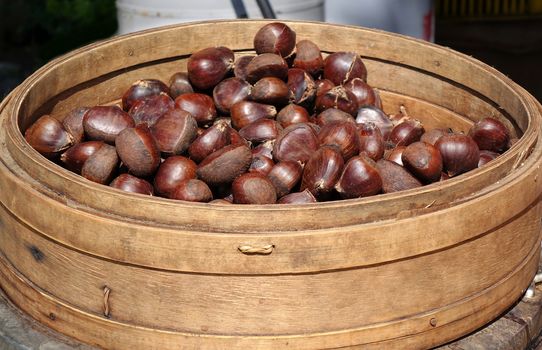 A vendor sells chestnuts cooked in a bamboo steamer