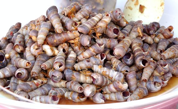 A street vendor sells boiled sea snails with red hot chili