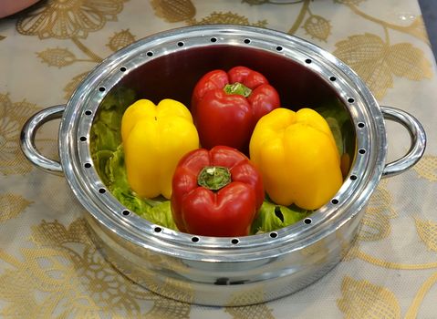 A stainless steel steam pot with bell peppers