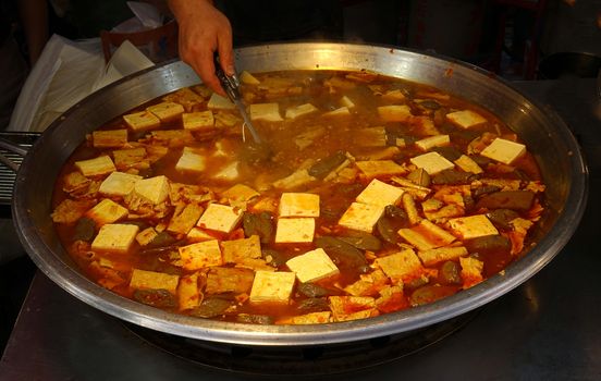 A street vendor sells a spciy stew with tofu and duck blood cakes

