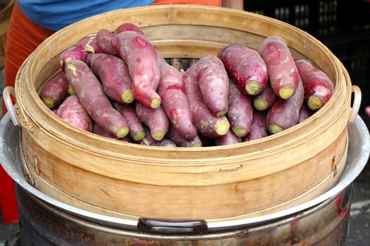 A street vendor sells sweet potatoes cooked in a bamboo steamer