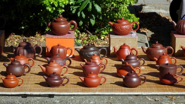 An outdoor vendor sells teapots made from characteristic red clay
