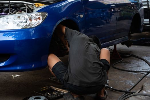 Car mechanic or serviceman disassembly and checking a disc brake and asbestos brake pads for fix and repair problem at car garage or repair shop