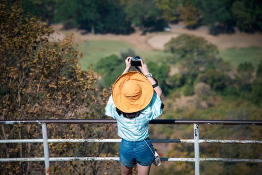 Asian pretty cute woman with hat relax and use smartphone at seaside city landscape viewpoint on mountain with happy and freedom emotion in concept travel, vacation, leisure in life