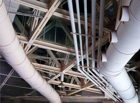 Interior ceiling view of girders and large ventilation pipes
