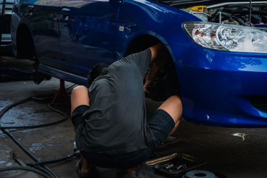 Car mechanic or serviceman disassembly and checking a disc brake and asbestos brake pads for fix and repair problem at car garage or repair shop