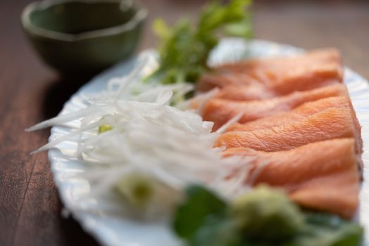 Japanese food delicacy consisting sashimi salmon of very fresh raw salmon fish sliced into thin pieces serving with radish sliced in japan restaurant