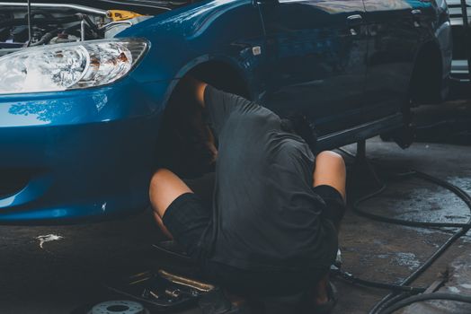 Car mechanic or serviceman disassembly and checking a disc brake and asbestos brake pads for fix and repair problem at car garage or repair shop