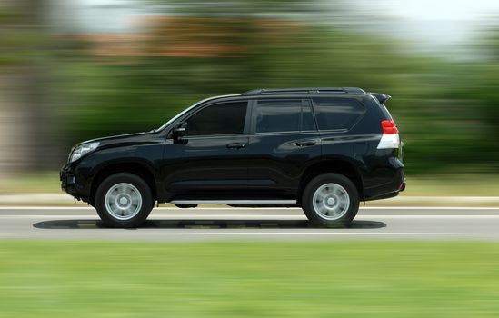 A panning shot of a speeding SUV