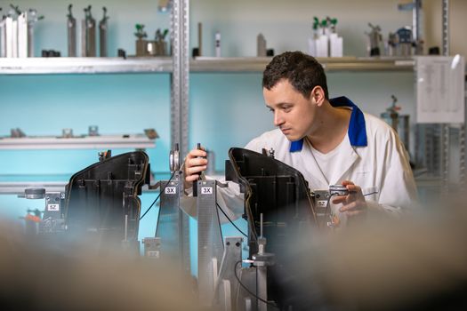 engineer measures plastic components for the production of lights for the automotive industry in a factory on a digital 3D machine.