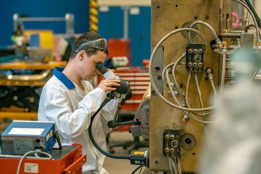 the engineer checks the correct setting of the metal mold for castings in the factory using a microscope.