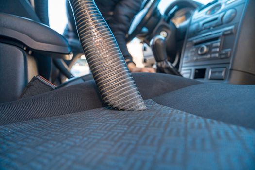 vehicle interior vacuum cleaning. Detail shot of an industrial vacuum cleaner cleaning a car seat.