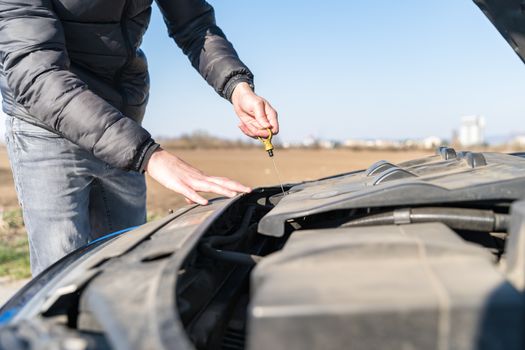 the driver checks the oil level in the car at fault on dirt road.