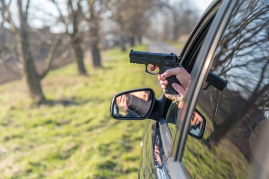 man aiming his gun from the window of a passenger car.