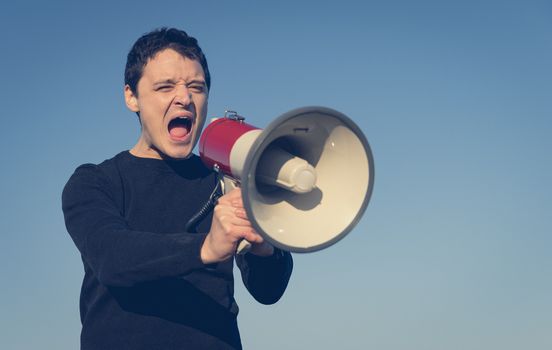 young man shouting into megaphone important message.