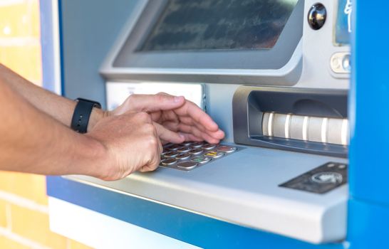 Entering a credit card pin on an ATM keyboard.