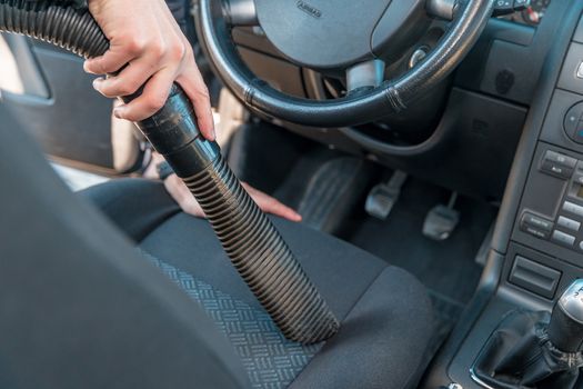 vehicle interior vacuum cleaning. Detail shot of an industrial vacuum cleaner cleaning a car seat.