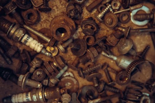 rusty bolts, nuts and spark plugs in a box in a car repair shop.