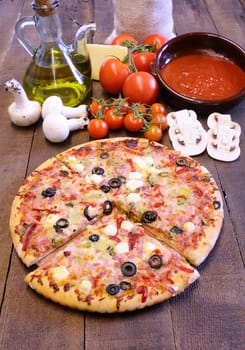 Pizza and ingredients on the kitchen table.