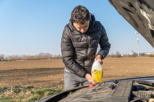 man pours into the car yellow liquid for the wiper.