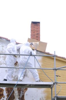 Men painting on a scaffold with protective clothing.