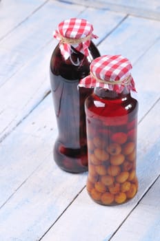 Jars with cherry liqueur on a wooden table