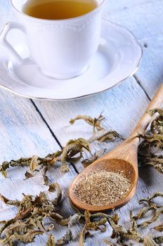 Cup of chamomile and herbs on wooden table in the kitchen.