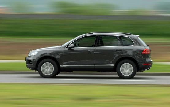 A panning shot of a speeding SUV