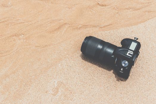 DSLR camera with telephoto lens on a beach it wet from water sea wave when travel and test using in the extreme environment demo waterproof by photographer