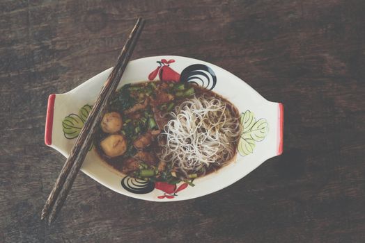 Braised beef clear noodle with meat balls soup stew (Ekaehla meat) with vegetable in bowl for sale at Thai street food market or restaurant in Thailand