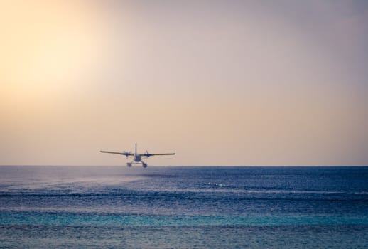 Private seaplane or hydroplane taking off during sunset time in the ocean lagoon. Maldives islands.
