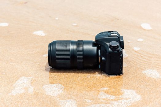 DSLR camera with telephoto lens on a beach it wet from water sea wave when travel and test using in the extreme environment demo waterproof by photographer