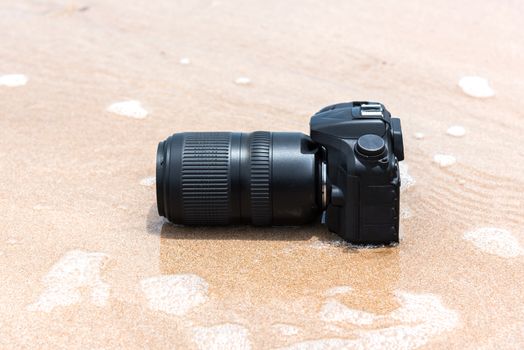 DSLR camera with telephoto lens on a beach it wet from water sea wave when travel and test using in the extreme environment demo waterproof by photographer