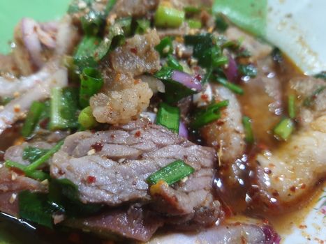 Spicy minced beef salad or Ground beef salad (Laab) is a Thai food for health consists of beef, ground rice, chili, lemon, onion and herb mixed in plate on a wood table at Thai street food