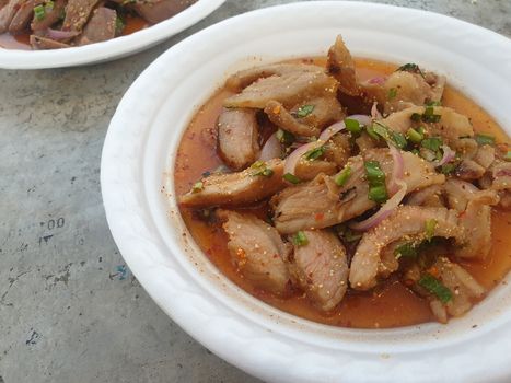 Spicy minced pork salad or Ground pork salad (Laab) is a Thai food for health consists of pork, ground rice, chili, lemon, onion and herb mixed in plate on a wood table at Thai street food