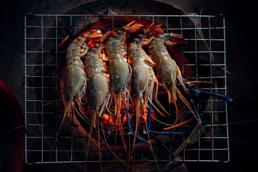 Grilled shrimp (Giant freshwater prawn) grilling with charcoal for sale at Thai street food market or restaurant in Bangkok Thailand