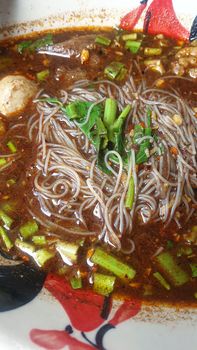 Braised beef clear noodle with meat balls soup stew (Ekaehla meat) with vegetable in bowl for sale at Thai street food market or restaurant in Thailand