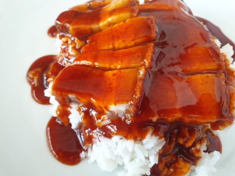 Barbecued red pork in sauce with rice and cucumber served in dish on wood table in Thai restaurant at Thai street food market at Bangkok Thailand