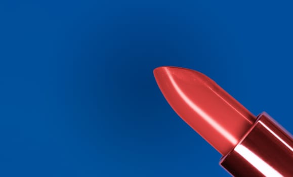 Beautiful bright red lipstick and classic blue complementary color on the background .