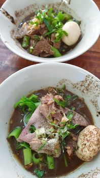 Braised beef clear noodle with meat balls soup stew (Ekaehla meat) with vegetable in bowl for sale at Thai street food market or restaurant in Thailand