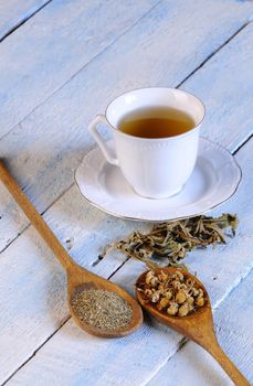 Cup of chamomile and herbs on wooden table in the kitchen.